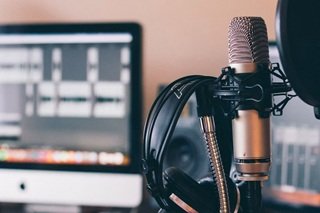 n independent artist tracking a vocal performance into a condenser microphone with a pop filter in a home recording studio setup.