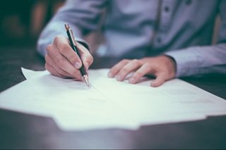 A close-up of a music producer signing a digital royalty split sheet agreement on a tablet screen in a dimly lit studio environment.