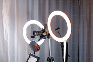 A camera with smartphone held in a professional ring light clip inside a music studio recording space, configured for capturing short-form video promotion clips.