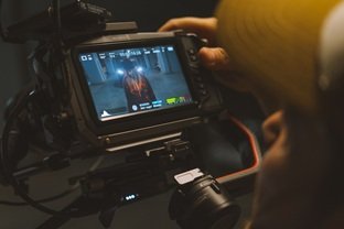 A camera operator viewing an artist on a cinema camera monitor during a music video shoot.