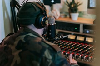Music artist wearing headphones in a recording studio with a microphone and mixing console.