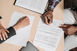 Two people reviewing and signing documents at a desk