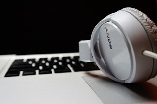 Studio headphones resting on an open laptop keyboard on a desk.