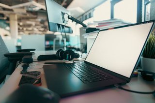 Laptop and headphones on a desk representing digital music distribution and release management.