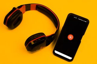YouTube Music app displayed on a smartphone next to headphones.